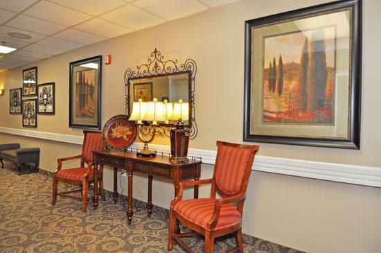 A cozy interior setting featuring a wooden table flanked by two red upholstered chairs, with artwork and a mirror adorning the wall.
