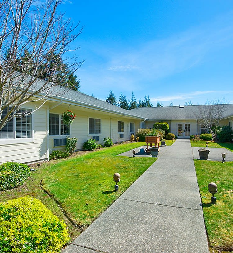 A residential building with a landscaped garden and pathway on a sunny day.