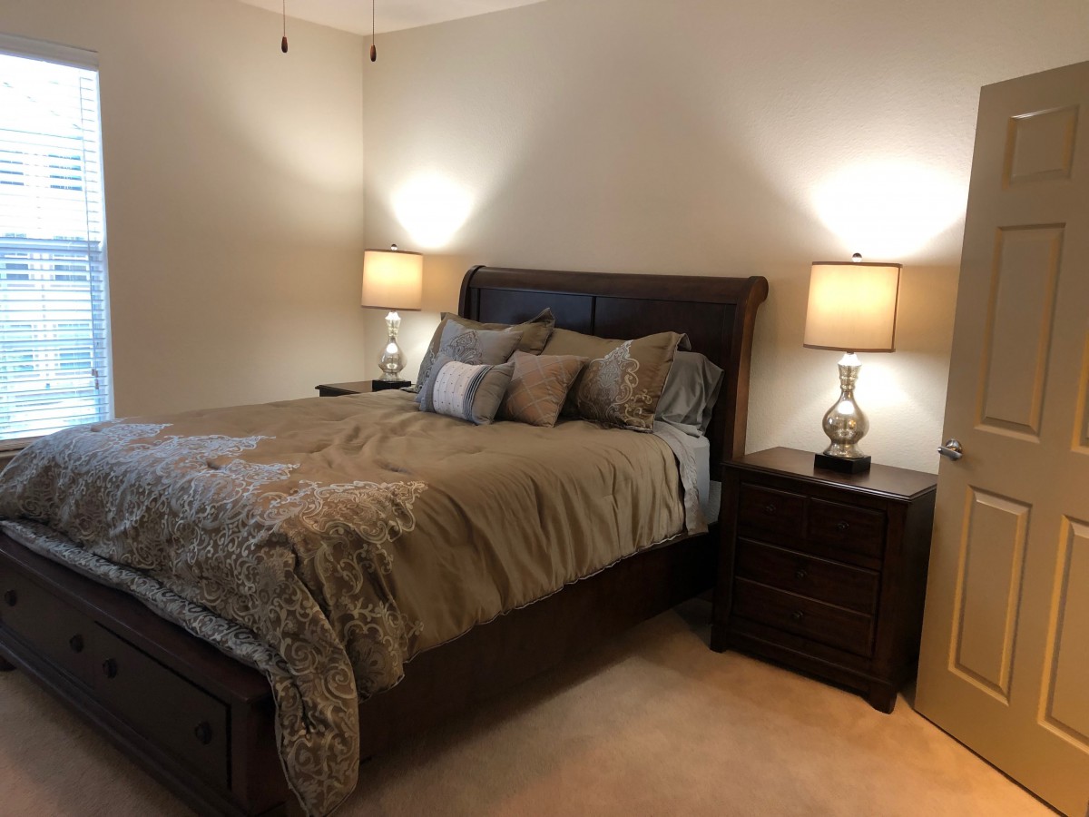 A cozy bedroom featuring a neatly made bed with bedside lamps on wooden nightstands.