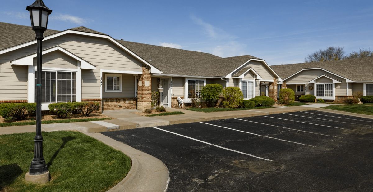 A view of suburban residential buildings with a parking lot in front.