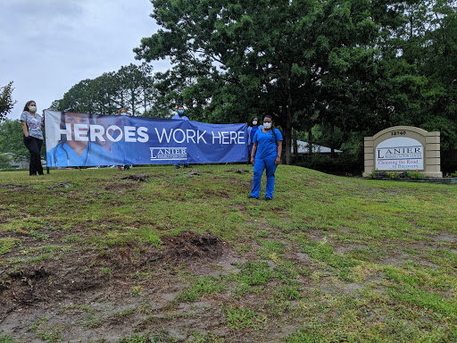 A worker in a blue outfit stands near a large banner that reads 'Heroes Work Here,' set against a grassy background.