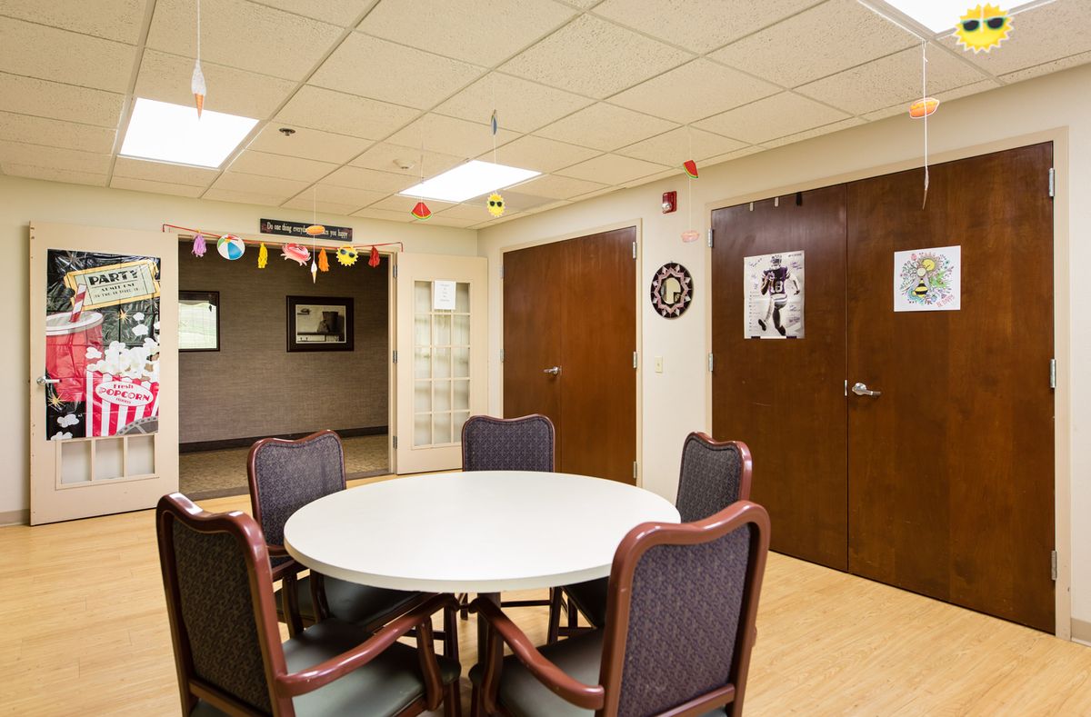 A meeting room with a round table and chairs, decorated with banners and ceiling lights.