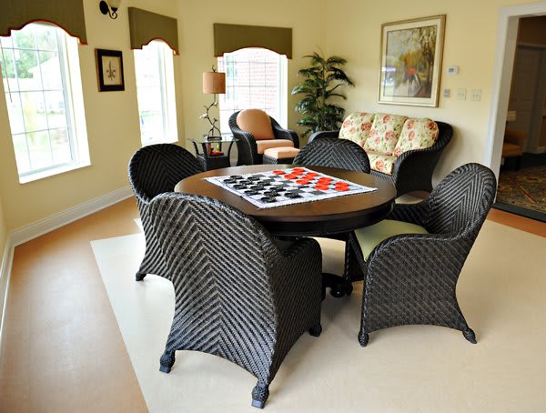A cozy living room setup featuring a round table with a checkerboard design surrounded by wicker chairs.