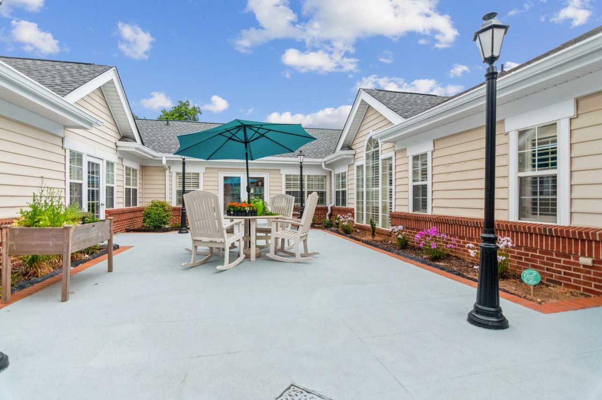 A spacious patio with outdoor furniture, including a table and chairs under an umbrella, in a residential courtyard.