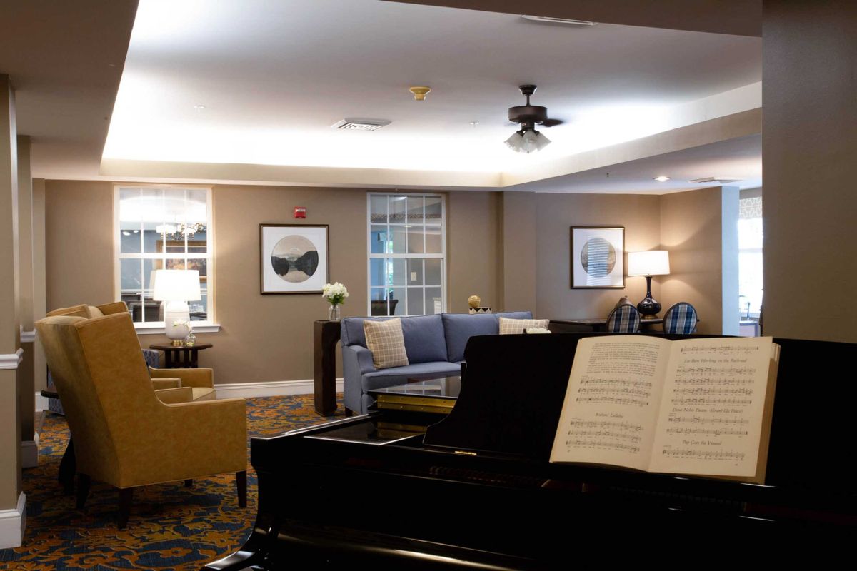 A cozy living room with a piano, comfortable seating, and tasteful decor.