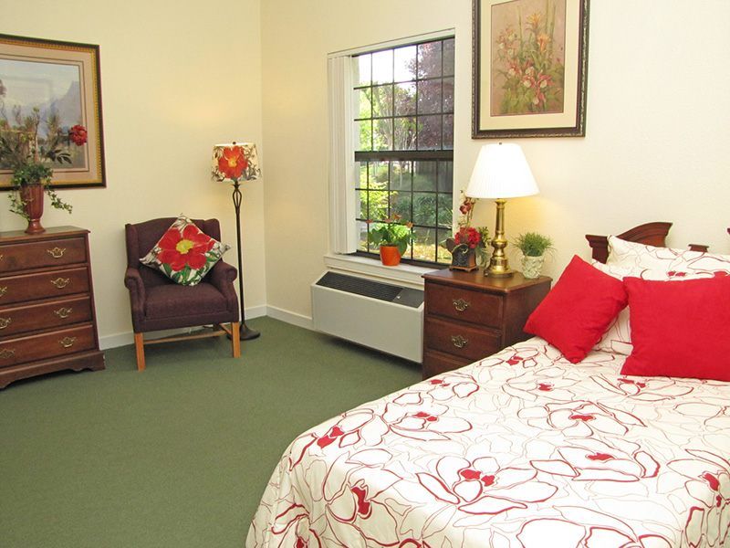 A cozy bedroom with a floral theme, featuring a neatly made bed, a comfortable chair, and tasteful decor.