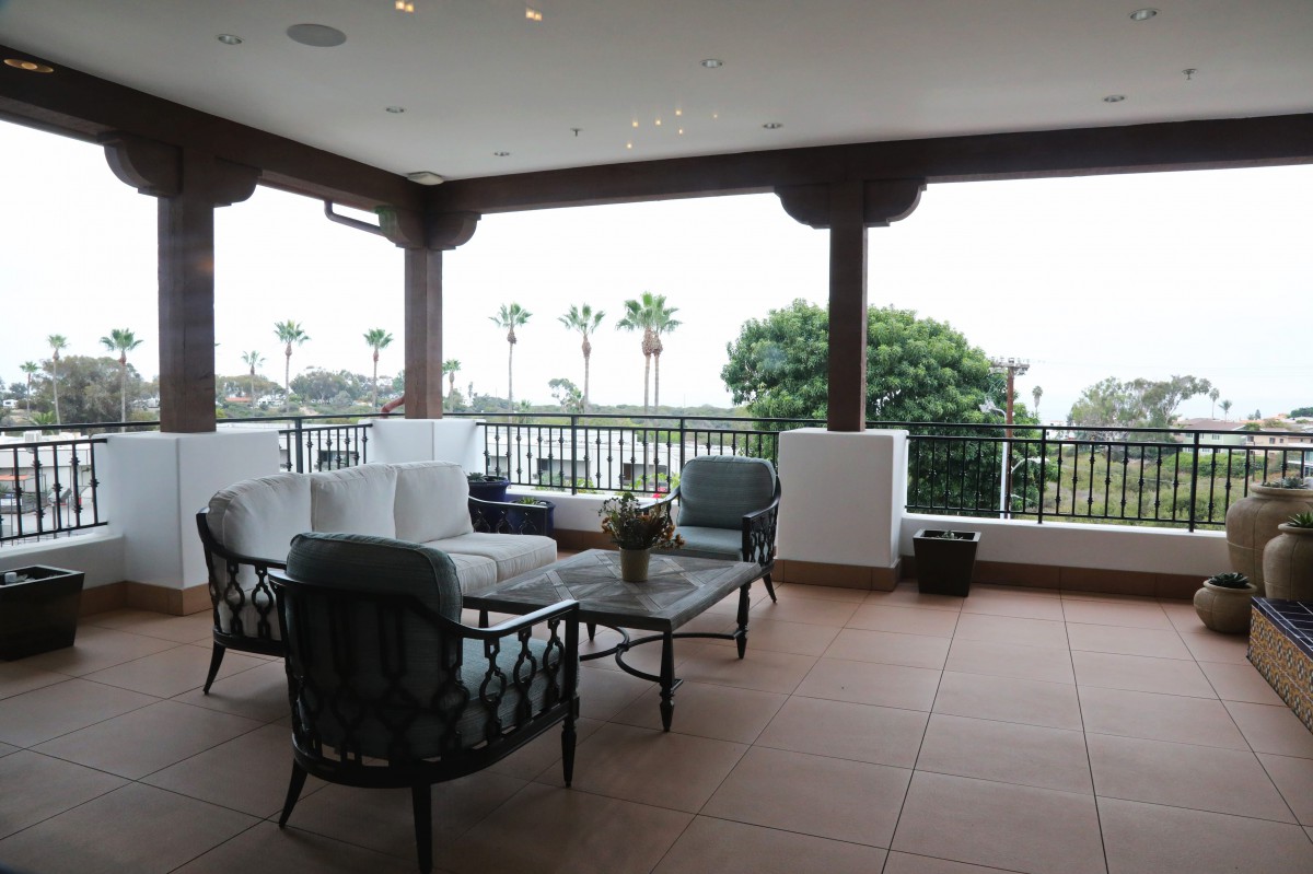 A spacious patio with comfortable seating overlooking palm trees and the ocean.
