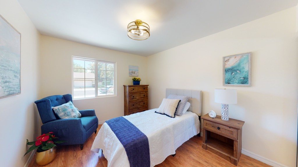 A cozy bedroom with a single bed, featuring blue accents and natural lighting.
