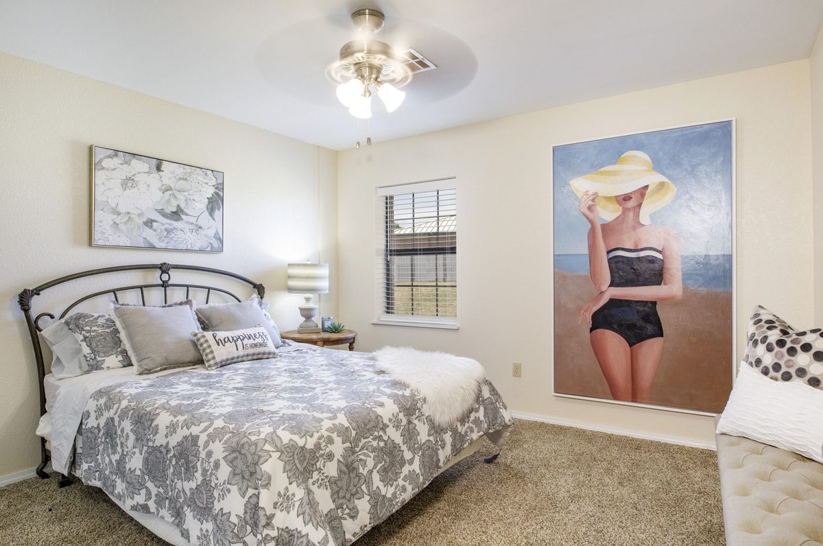 A cozy bedroom featuring a large artwork of a woman on the wall, with a neatly made bed and stylish decor.