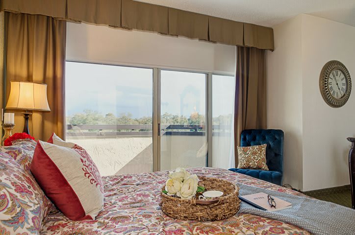 A cozy bedroom with a large window showcasing a scenic view.
