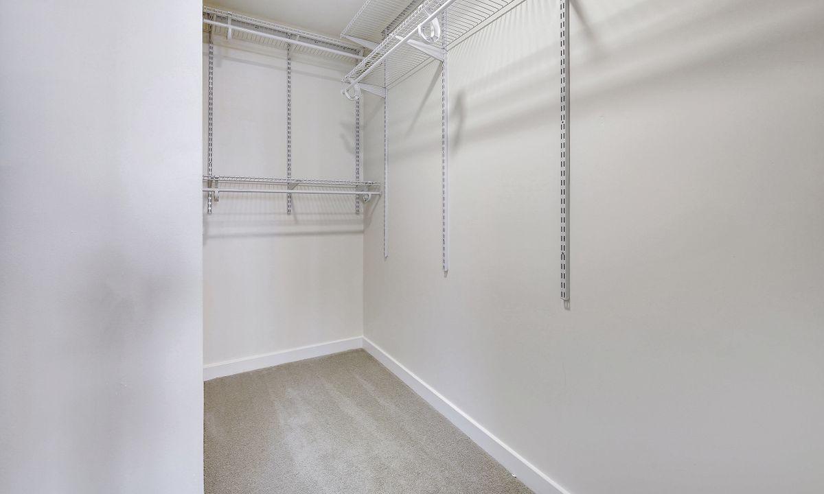 Empty walk-in closet with shelving and hanging rods.