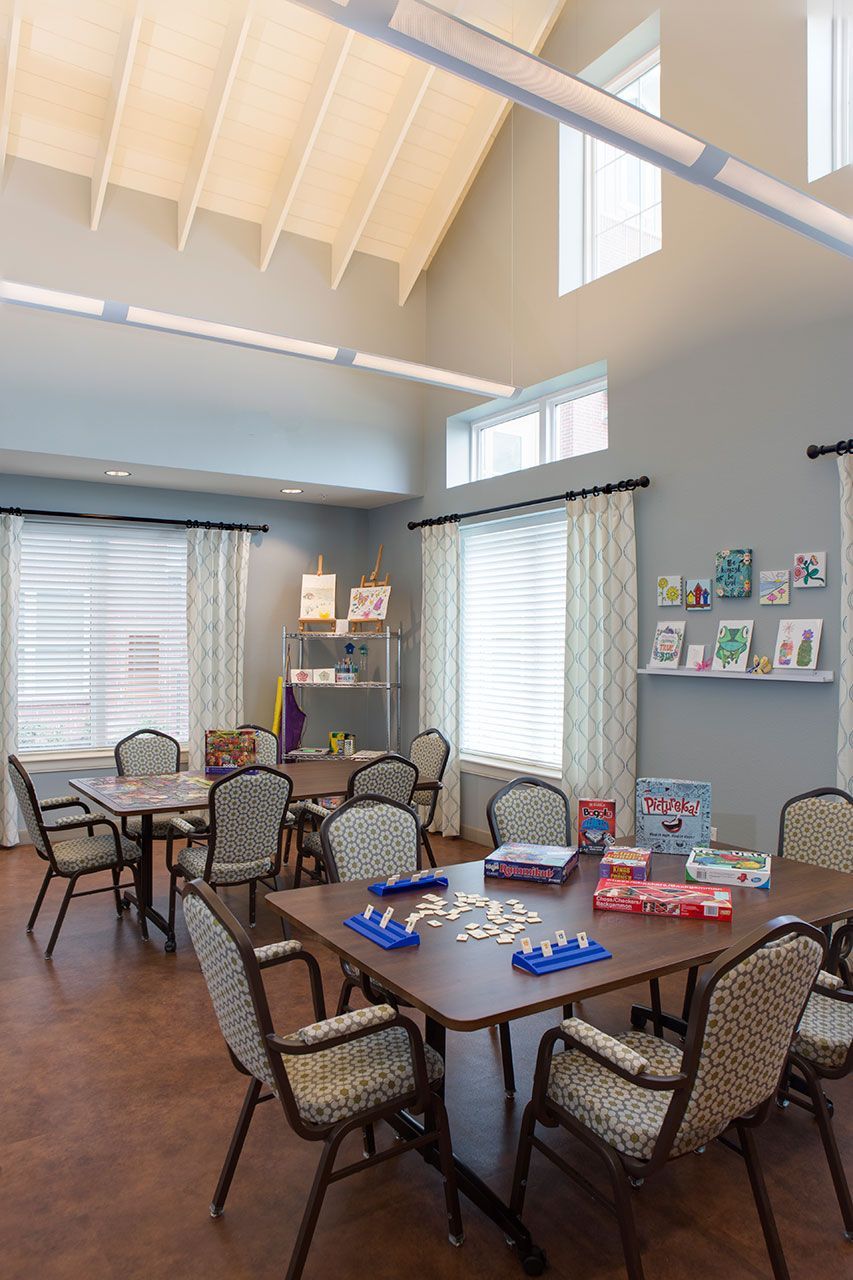 A community room with tables, chairs, and games set up for activities.