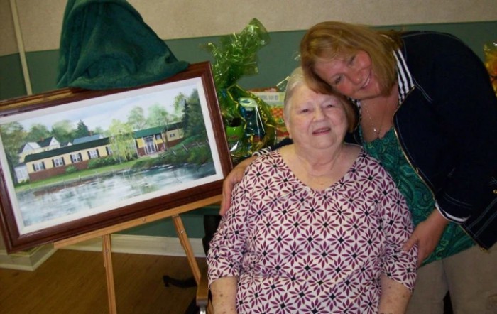 Two people posing happily with a framed painting.