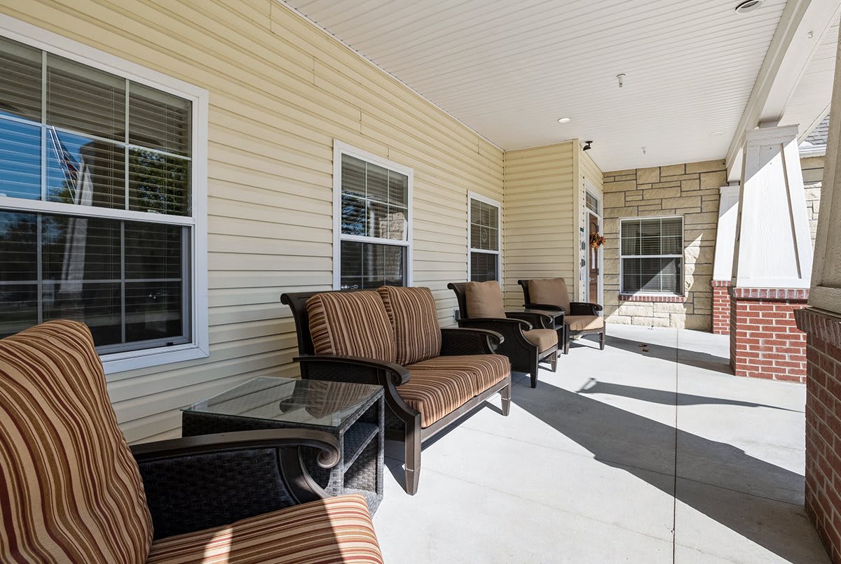 A cozy outdoor porch with comfortable seating and windows.