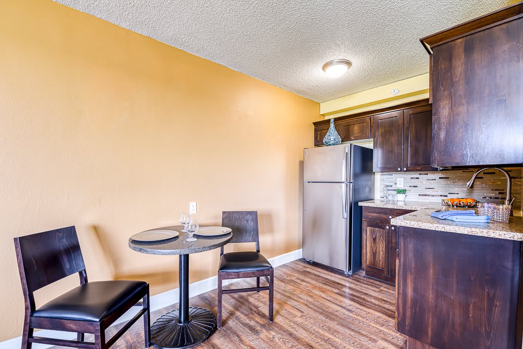 A cozy kitchen with a small dining table, wooden cabinets, and stainless steel appliances.
