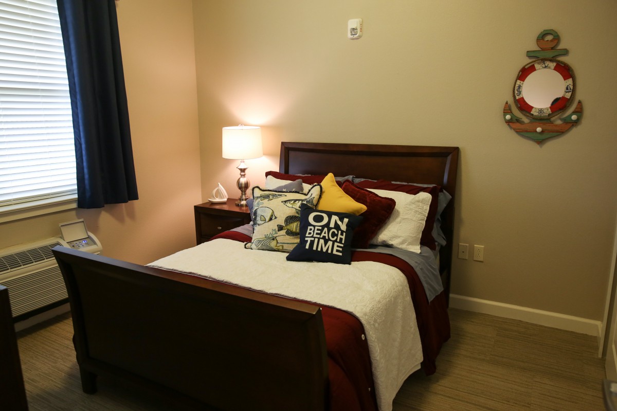 Cozy bedroom with neatly arranged pillows and a bedside lamp.