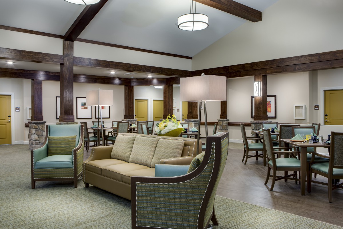 A spacious lounge area with comfortable seating and dining tables, featuring modern lighting and wooden beams.