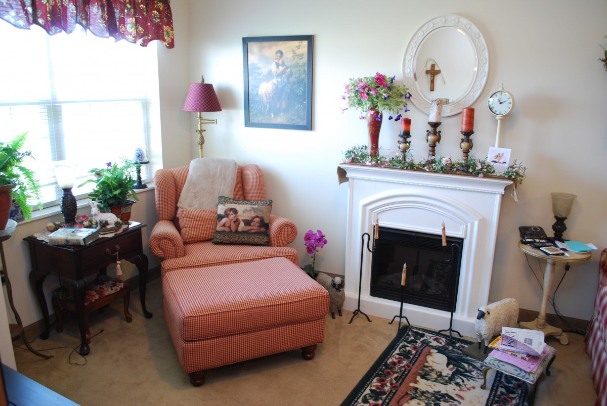 Cozy living room corner with an armchair and fireplace, adorned with decorative elements and a painting.