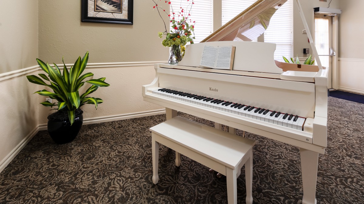 A beautifully decorated living room featuring a white grand piano with sheet music on the stand.