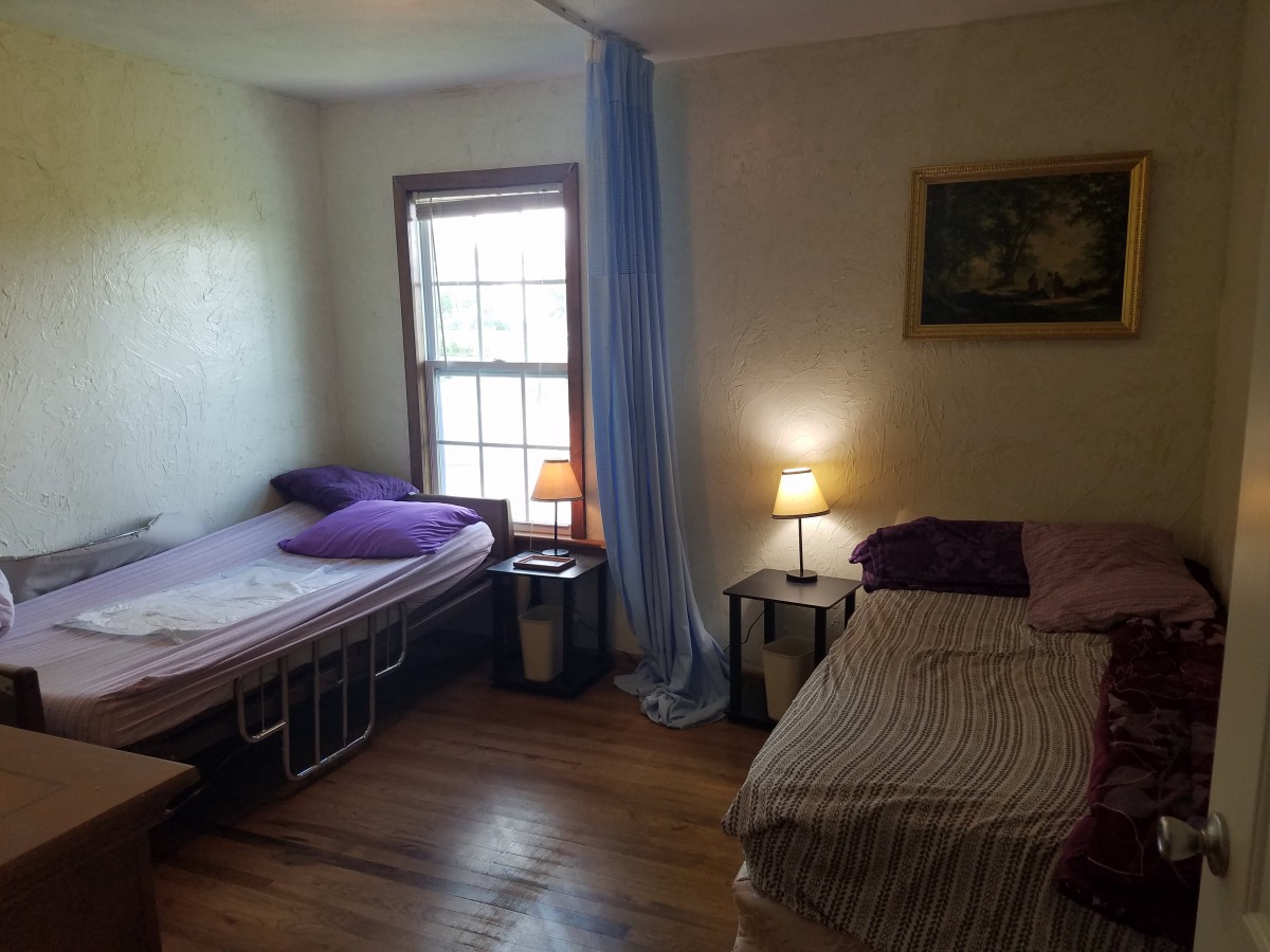 A cozy bedroom with two beds, wooden floor, and soft lighting.