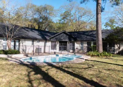 A cozy house with a swimming pool in the backyard, surrounded by trees.