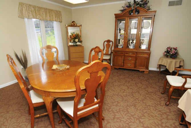 A cozy dining room featuring a wooden table with matching chairs and a display cabinet.