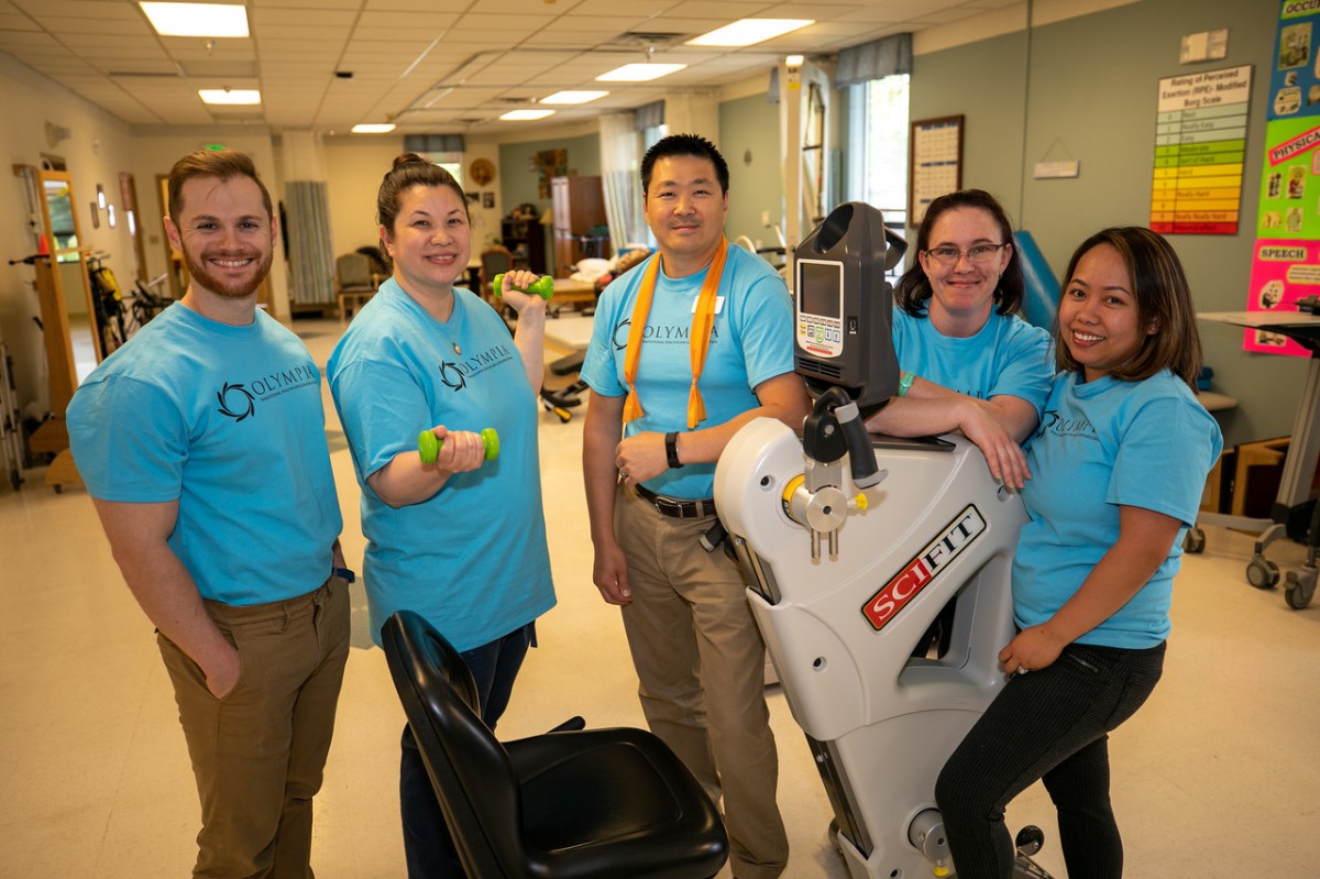 A team of healthcare professionals posing with a rehabilitation robot.