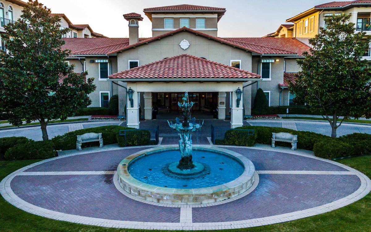 A picturesque view of a grand building with a central fountain surrounded by gardens.
