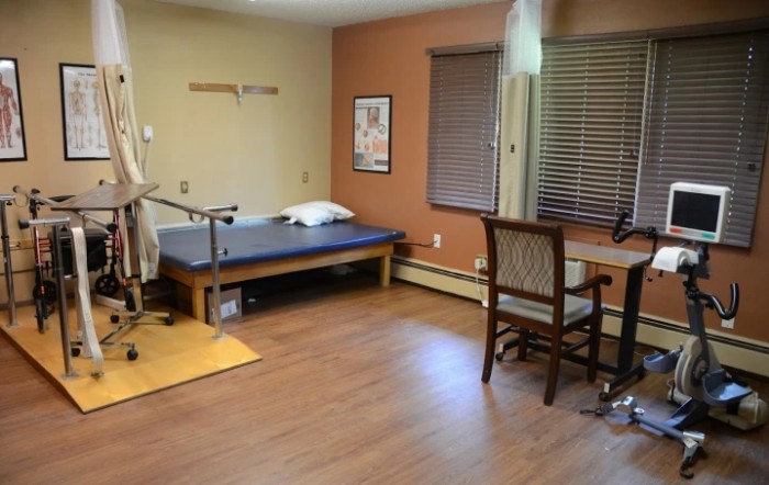 A therapy room equipped with a treatment table and exercise equipment for physical rehabilitation.