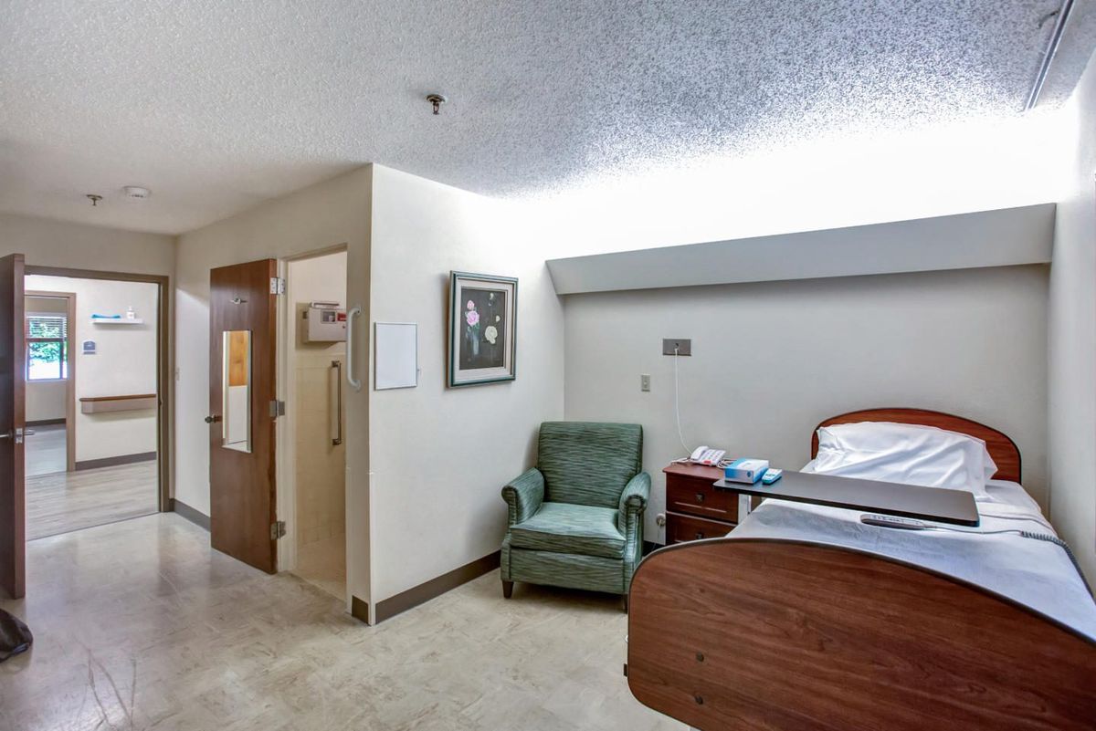 A clean and organized hospital room with a bed, chair, and minimal decorations.