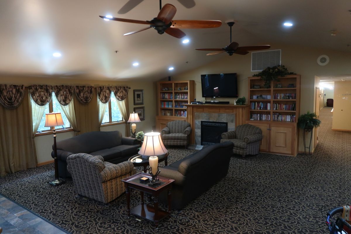 A cozy living room featuring multiple sofas, a fireplace, bookshelves, and a television.