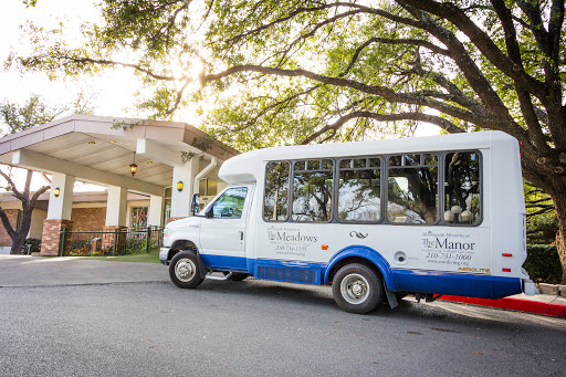 A shuttle bus parked outside a facility, surrounded by greenery.