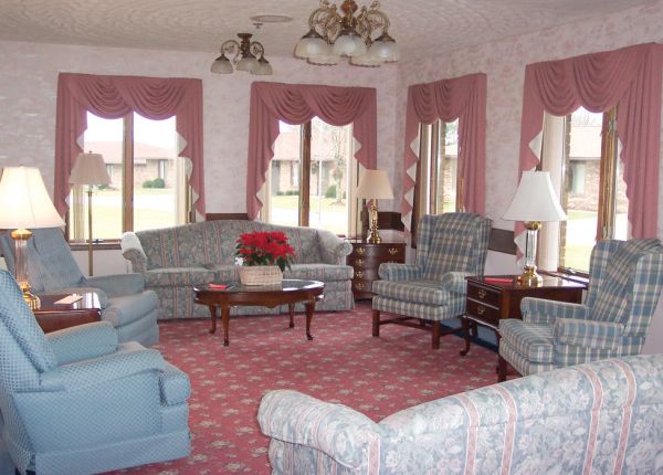 A vintage-style living room with floral-patterned sofas and armchairs, complemented by a coffee table and lamps.