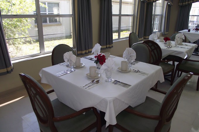 A neatly set dining table with a white tablecloth and elegant place settings in a well-lit restaurant.