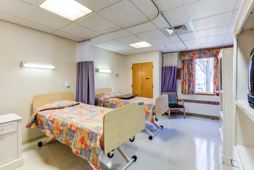A view of a hospital patient room featuring two beds and a bright, clean interior.