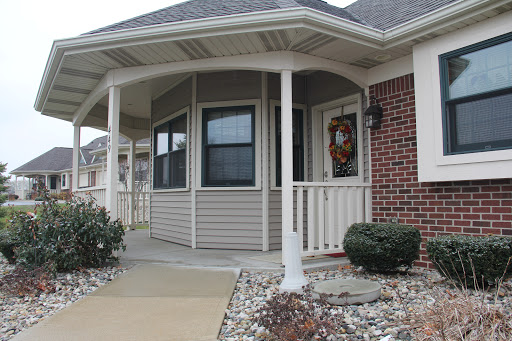 A welcoming porch with a decorative wreath, showcasing a blend of brick and siding on a beautiful residential home.
