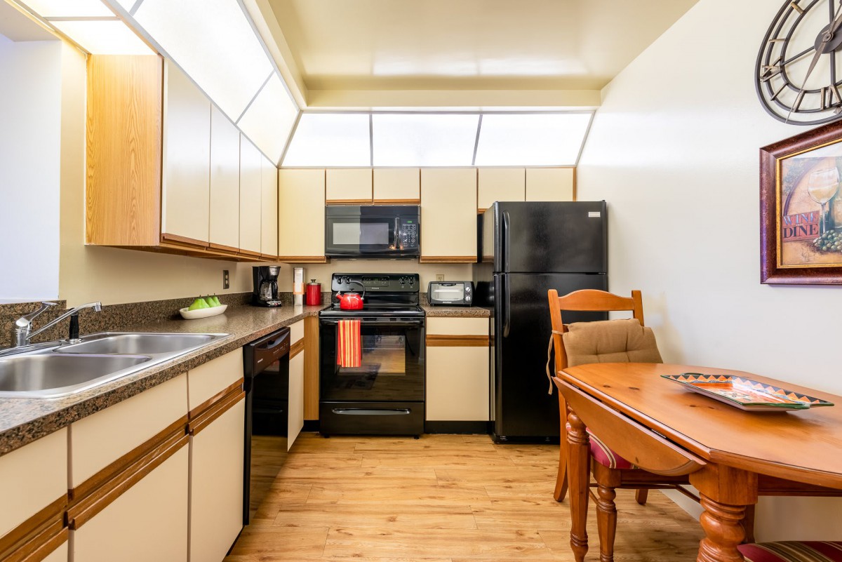 A modern kitchen with black appliances and a wooden dining table.