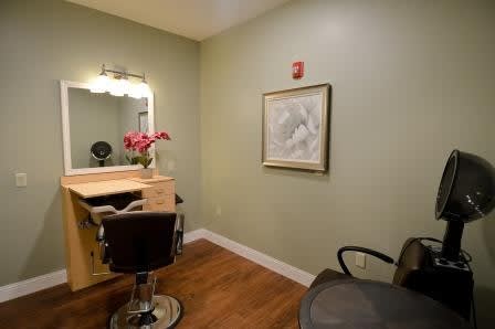 A cozy hair salon setup with a mirror, chairs, and decorative elements like flowers and wall art.