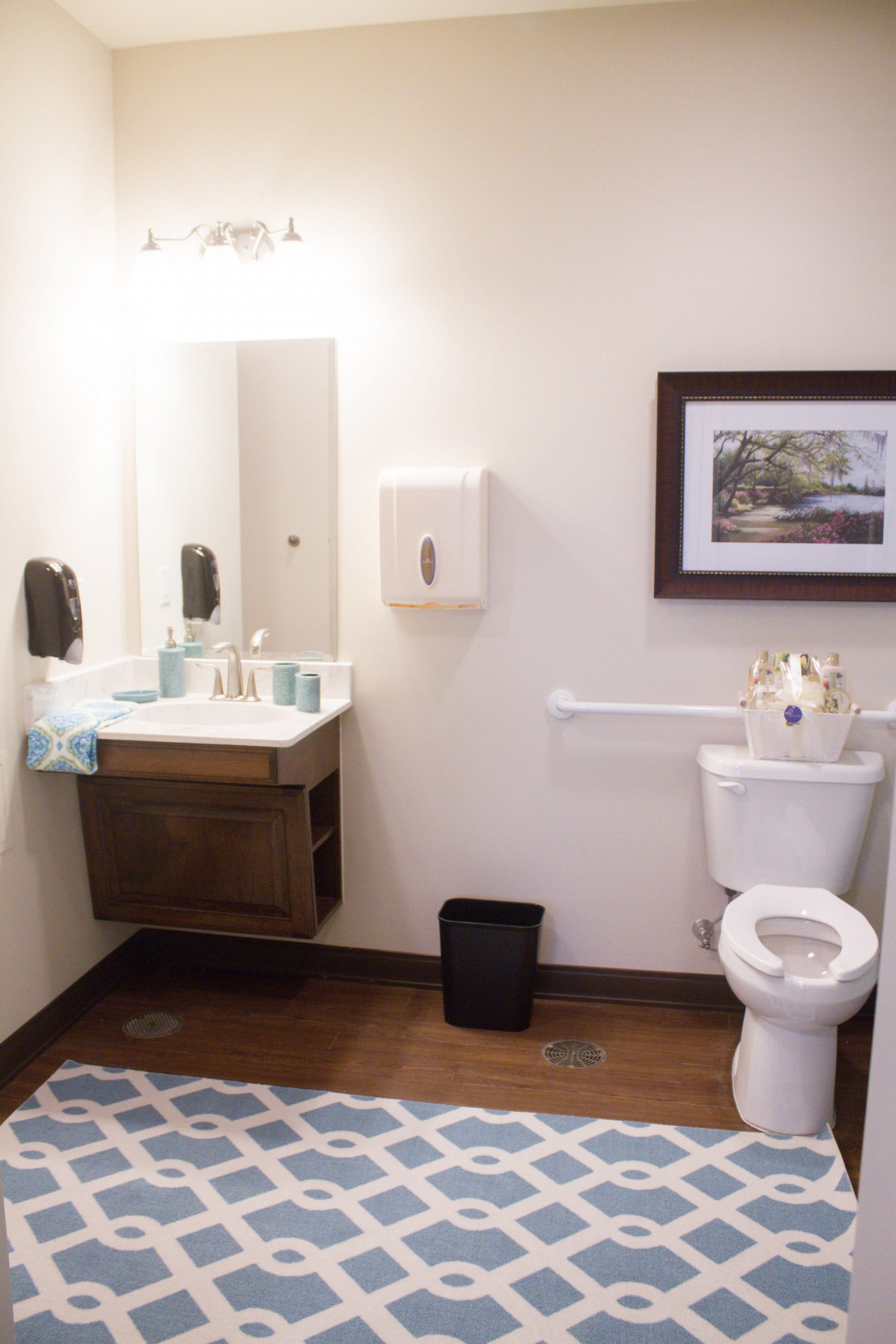 A clean and well-organized bathroom featuring a sink, toilet, and wall art.