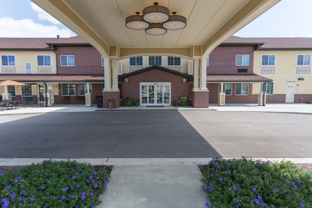 A residential building entrance with a covered pathway and landscaped surroundings.