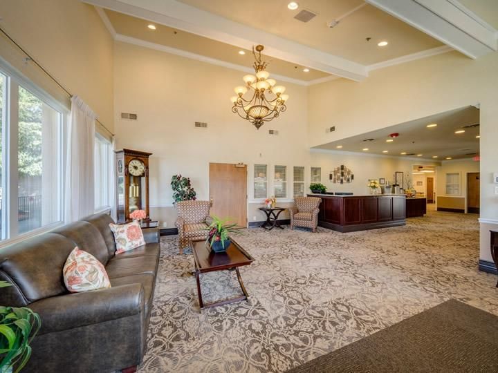 A spacious and elegantly decorated lobby with a chandelier, comfortable seating, and a reception desk.