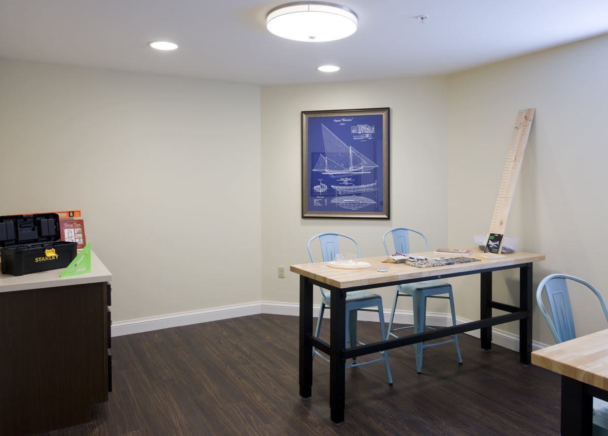 A modern office space with a table, chairs, and framed artwork on the wall.