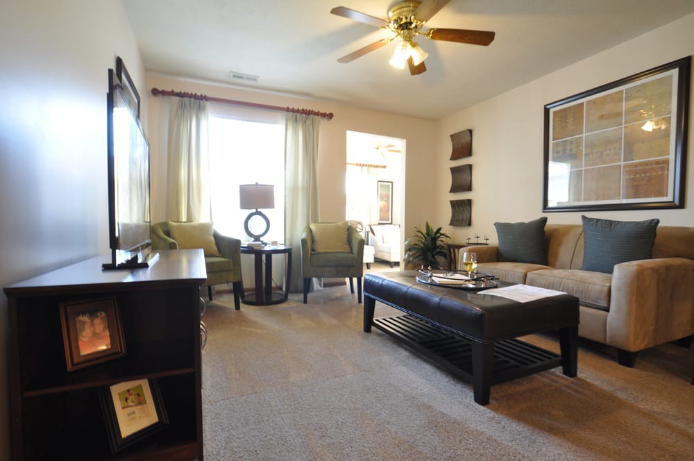 A cozy living room featuring a sofa, coffee table, and ceiling fan, with natural light streaming through the window.