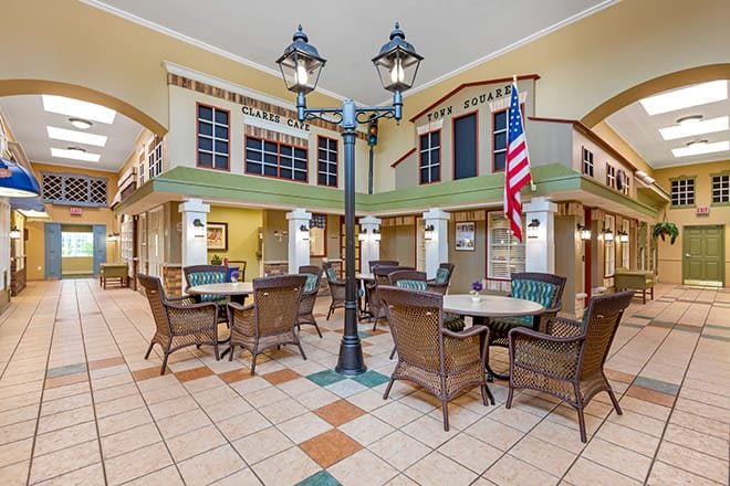 A spacious indoor seating area with wicker chairs, tables, a lamppost, and an American flag.