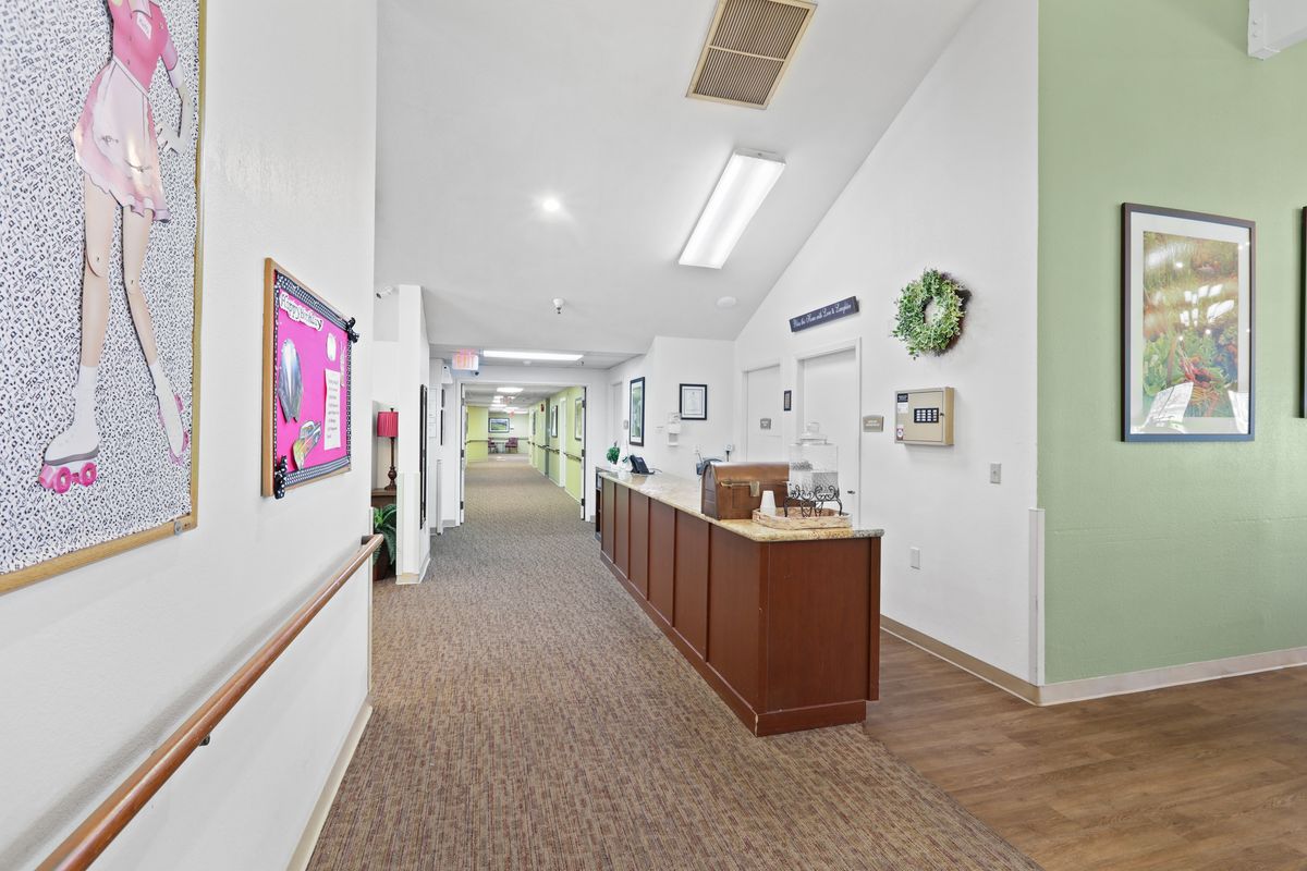 A well-lit hallway with a reception desk and decorative elements on the walls.