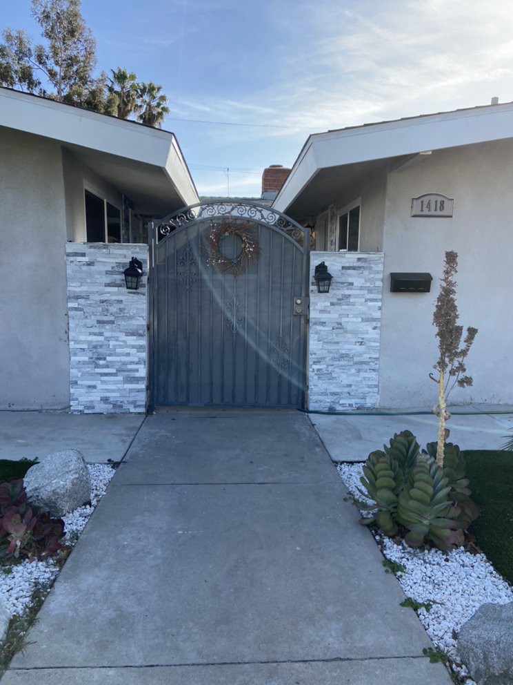 Modern house entrance with a metal gate and stone walls.