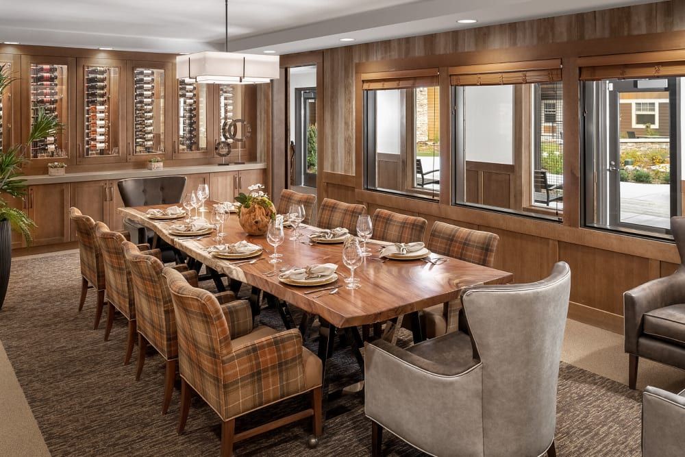 A cozy dining room with a large wooden table and upholstered chairs set for a meal.