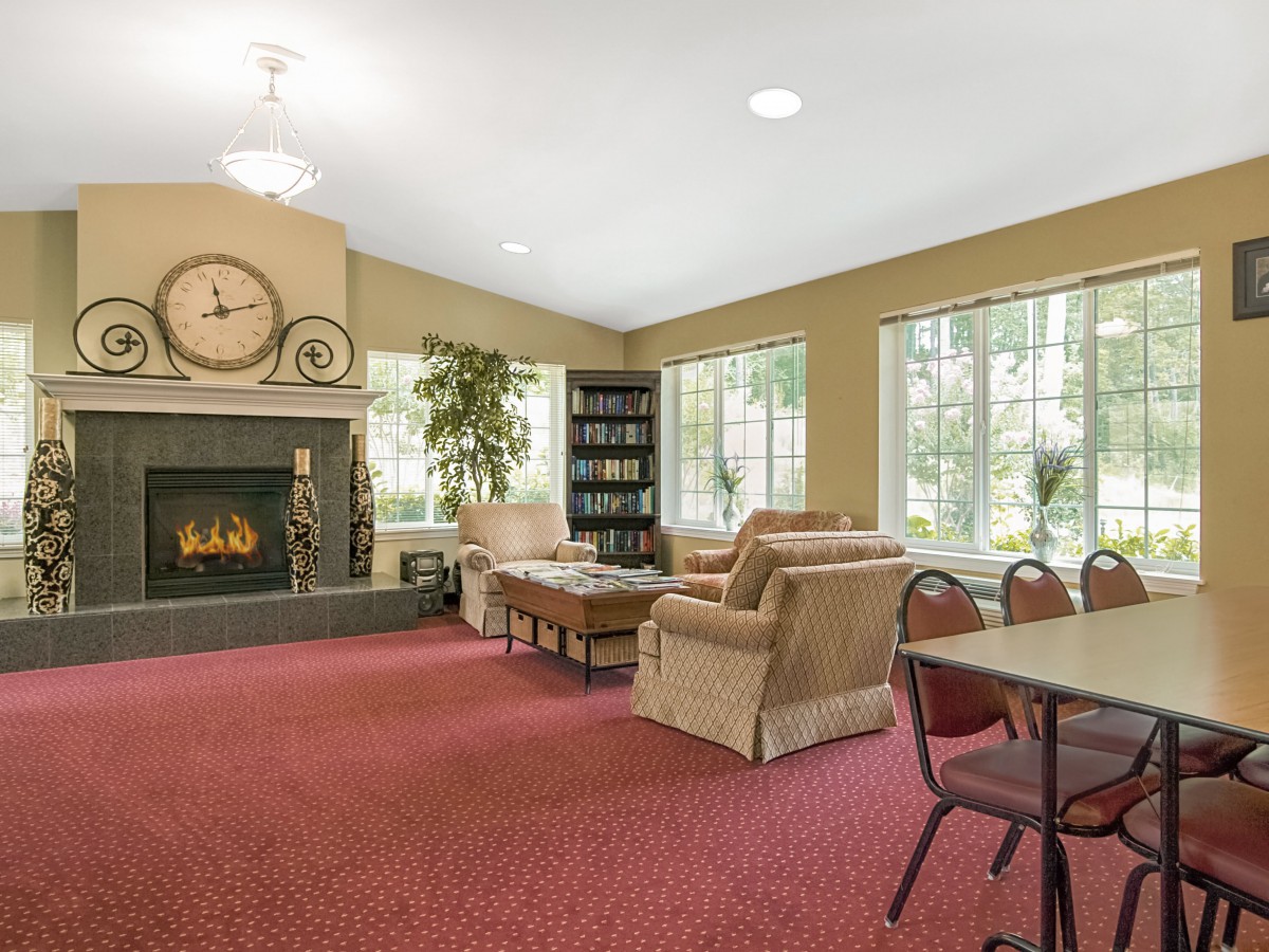 A cozy living room with a fireplace, comfortable seating, and large windows.