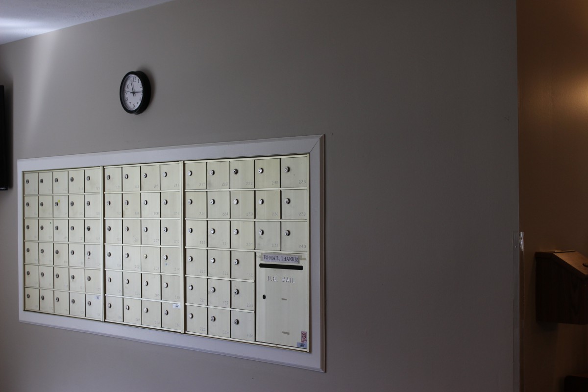 A wall of mailboxes with a clock above.