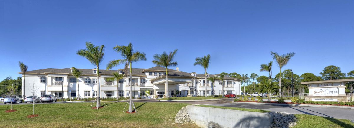 A modern building surrounded by palm trees under a clear blue sky.